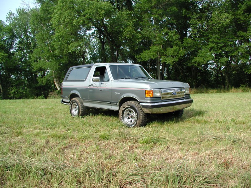 Ford Bronco parked in a grassy field with trees in the background