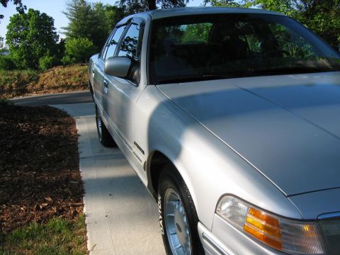 1985 Ford LTD Crown Victoria - Silver sedan parked on a concrete driveway. The body style suggests a 1990s Ford Crown Victoria.