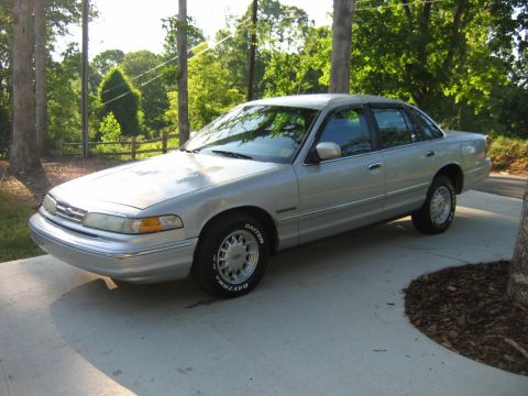 1985 Ford LTD Crown Victoria - This silver sedan, likely a 1992 model based on its body style, is shown from the front three-quarter angle.