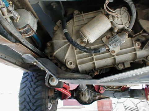 1996 Ford Bronco - Close-up view of the transmission and transfer case assembly, including the skid plate, on a vehicle's undercarriage.
