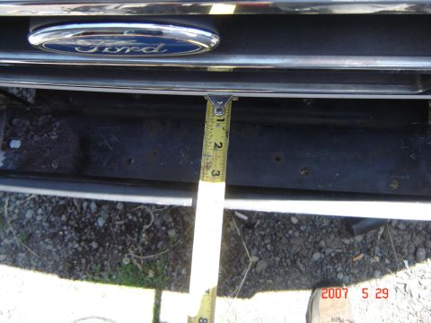 1993 Ford Bronco - Close-up of a Ford emblem on a vehicle grille, with a tape measure for scale.