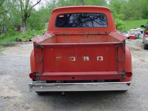 1965 Ford F-100 - This red Ford pickup truck shows its rear end, with the iconic 'FORD' lettering on the tailgate.