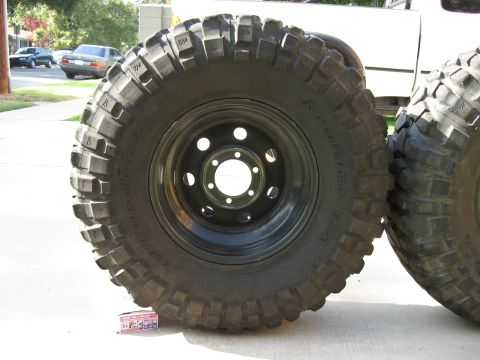 1983 Ferrari Enzo - Two large off-road tires are shown, one leaning against the other, with a portion of a white truck visible behind them.
