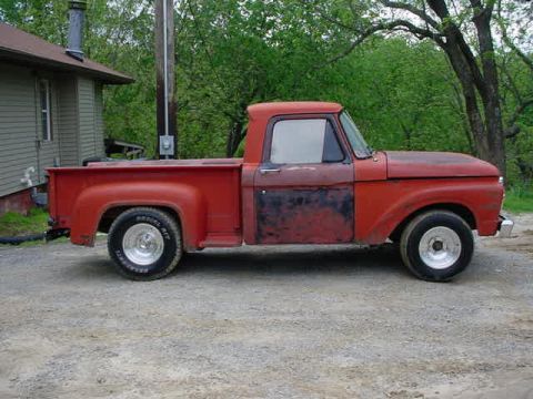 1965 Ford F-100 - Side view of a 1965 Ford F-100 pickup truck with red paint and aftermarket wheels.