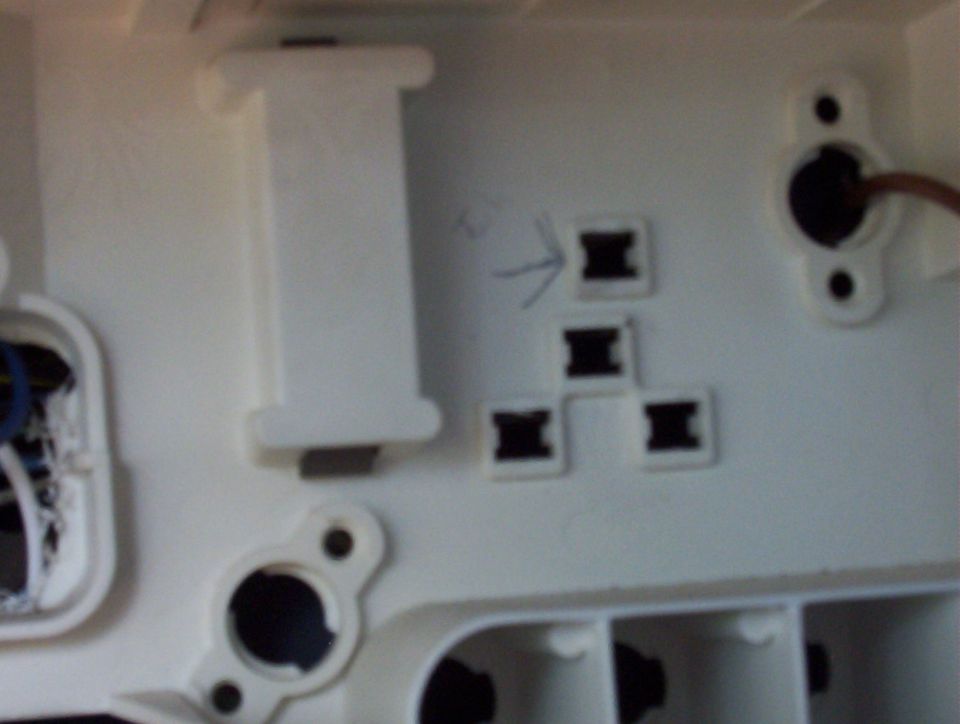 Back of white plastic panel with square terminal sockets, a drawn arrow pointing to one, and a brown wire