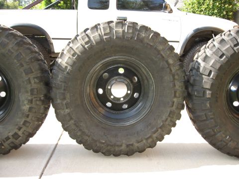 1983 Ferrari Enzo - Off-road tires are displayed in front of a white pickup truck, with a watermark reading 'SUPERMOTORS'.