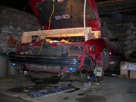 1992 Ford Taurus - Front end of a 1992 Ford Taurus SHO undergoing repairs in a garage.
