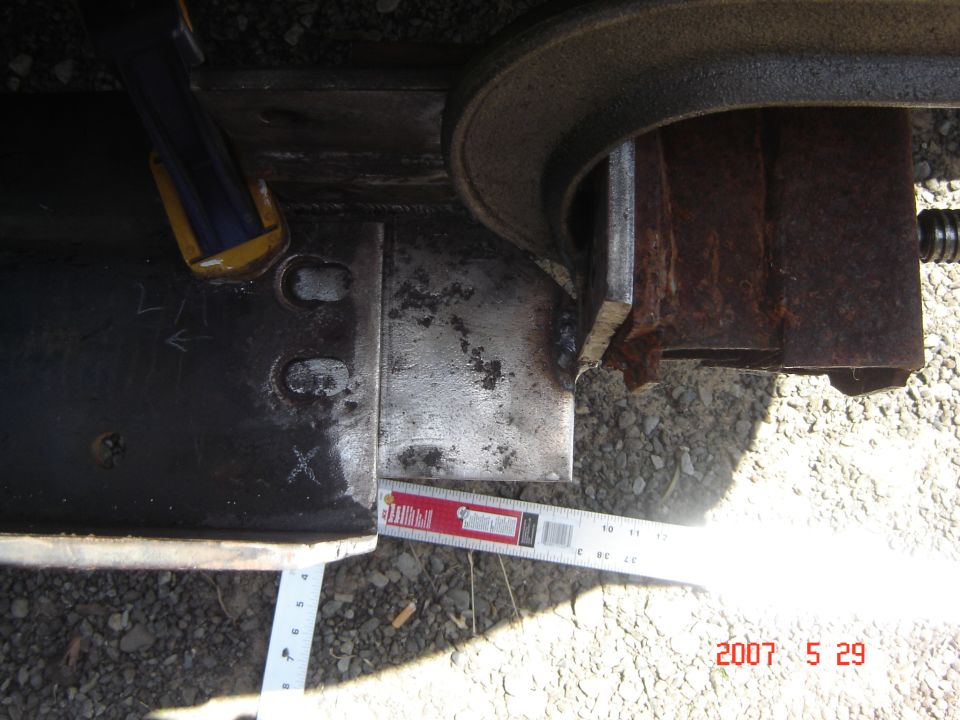 Metal bracket clamped and measured with a ruler, showing rust and welds