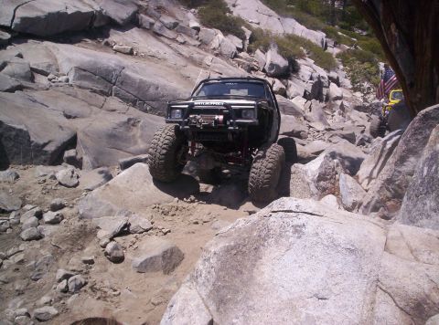 1989 Ford Bronco - Front view of a black mini-truck rock buggy descending a granite slab trail, fitted with a tube front bumper and winch, stinger hoop, red-a…