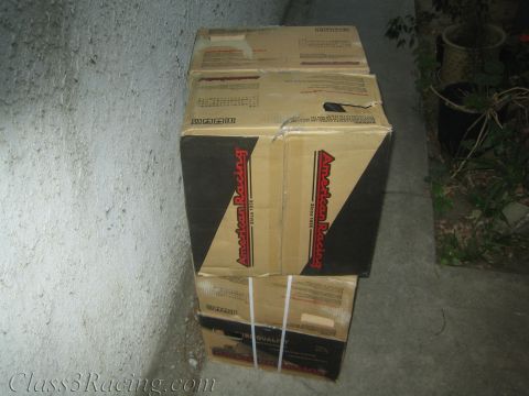1990 Ford Bronco - Two cardboard shipping boxes printed with the American Racing logo are stacked on a concrete floor against a stucco wall.