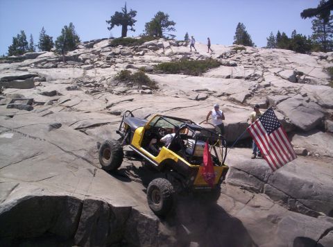 1989 Ford Bronco - Off-road vehicle navigates rocky terrain while flying the American flag.