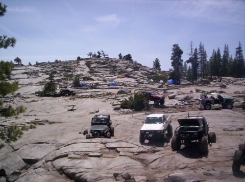 1989 Ford Bronco - Multiple off-road vehicles and tents are set up in a rocky, outdoor campsite.