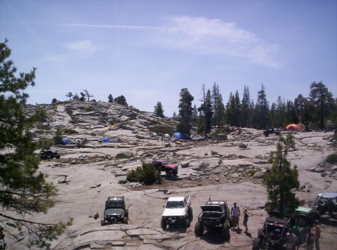 1989 Ford Bronco - Off-road vehicles and tents at a campsite on a sunny day.