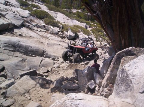 1989 Ford Bronco - Off-road buggy tackles a challenging rocky incline in a mountainous landscape.