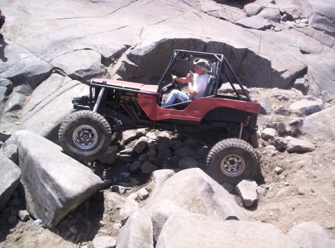 1989 Ford Bronco - A driver in a red off-road vehicle maneuvers through a challenging rocky landscape.
