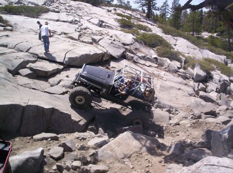 1989 Ford Bronco - An off-road vehicle navigates a challenging rocky terrain on a sunny day.