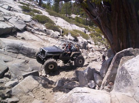 1989 Ford Bronco - A heavily modified Jeep navigates a challenging rocky terrain on an off-road trail.