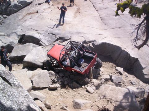 1989 Ford Bronco - This heavily modified off-road vehicle is shown tackling a challenging rocky obstacle.