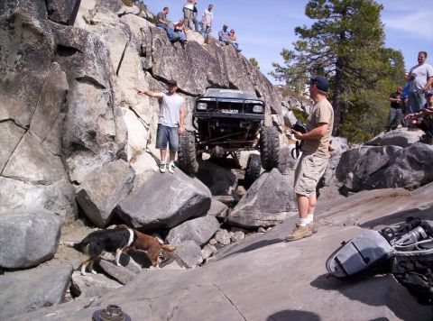 1989 Ford Bronco - A modified off-road vehicle tackles a challenging rocky obstacle with spectators watching from above.