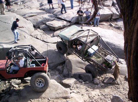 1989 Ford Bronco - Off-road vehicles tackle a challenging rocky course with spectators observing the action.