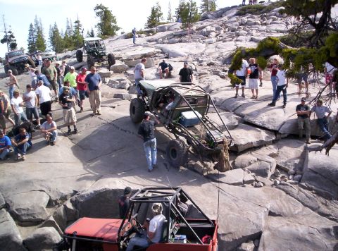 1989 Ford Bronco - Several custom off-road vehicles are being driven over large rocks, with a crowd of people watching the event.