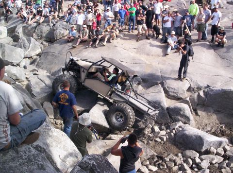 1989 Ford Bronco - An off-road buggy navigates a challenging rocky terrain, drawing a crowd of onlookers.