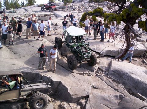 1989 Ford Bronco - A group of people watch as an off-road buggy navigates a rocky terrain.