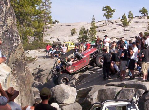 1989 Ford Bronco - Off-road vehicle navigates a challenging rocky terrain with spectators observing the action.