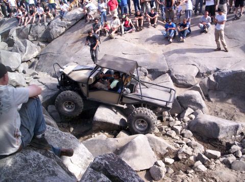 1989 Ford Bronco - A crowd watches as a custom off-road vehicle navigates a challenging rocky terrain.