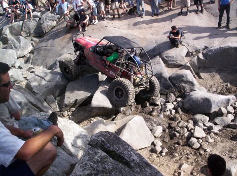 1989 Ford Bronco - Custom off-road buggy tackles a challenging rock crawling course with onlookers observing.