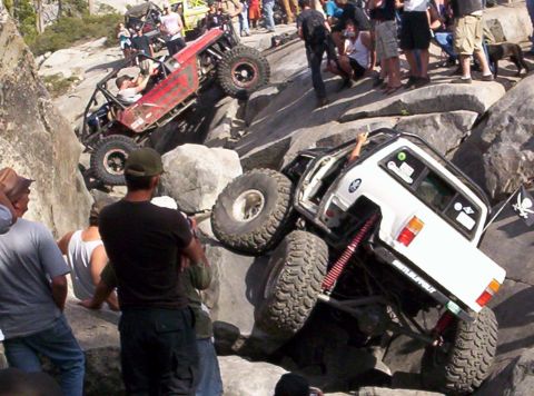 1989 Ford Bronco - Off-road vehicles navigate a challenging rocky terrain with a crowd observing the action.