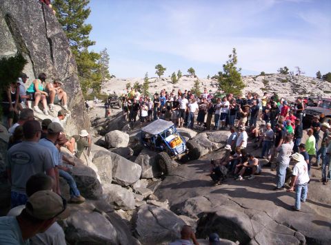 1989 Ford Bronco - A crowd watches an off-road vehicle traverse a challenging rocky terrain under a clear sky.