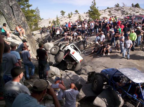 1989 Ford Bronco - Spectators watch as off-road vehicles tackle a challenging rocky course.