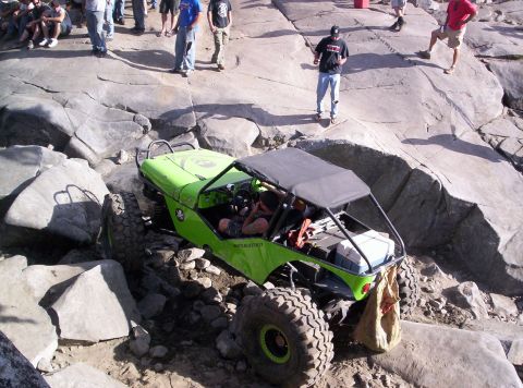 1989 Ford Bronco - This modified jeep is tackling a challenging rocky terrain with spectators watching from above.