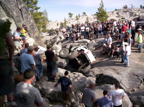 1989 Ford Bronco - An off-road vehicle is stuck on rocks, surrounded by spectators.