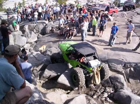 1989 Ford Bronco - A group of spectators watches an off-road vehicle traverse a rocky terrain.