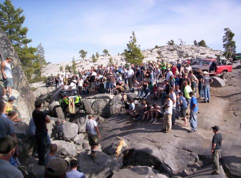 1989 Ford Bronco - A group of people gather to watch an off-road vehicle traverse a challenging rocky landscape.
