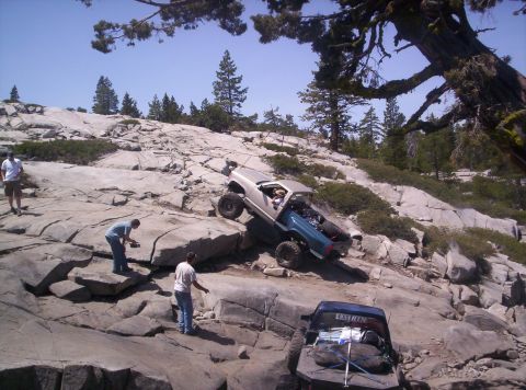 1989 Ford Bronco - Off-road vehicles navigate a challenging rocky terrain under a clear blue sky.