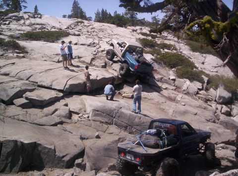 1989 Ford Bronco - Off-road vehicles tackle a challenging rocky incline, with spectators observing the difficult climb.