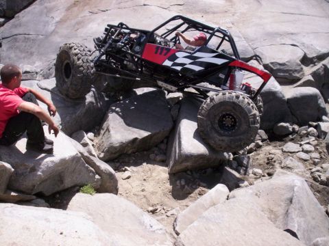 1989 Ford Bronco - A custom off-road buggy navigates a challenging rocky terrain with a spectator observing the action.
