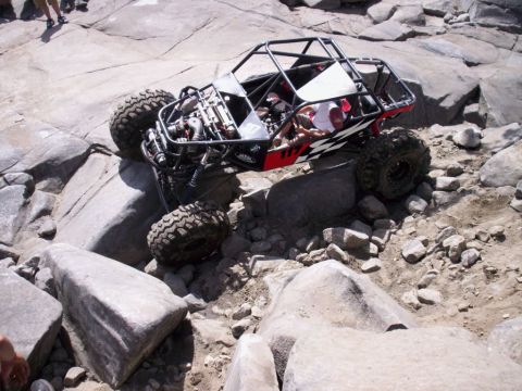 1989 Ford Bronco - Custom buggy with large tires climbs over boulders on a rocky trail.