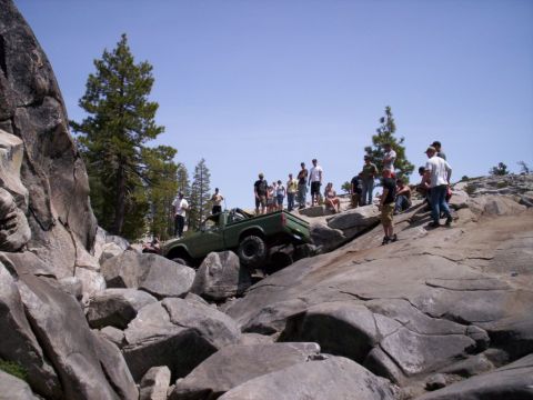 1989 Ford Bronco - A group watches as a modified pickup truck attempts to climb a steep, rocky terrain.