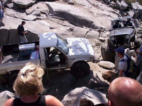 1989 Ford Bronco - Two off-road vehicles navigate a rocky trail, with one pickup truck appearing to be stuck.