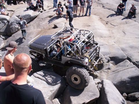 1989 Ford Bronco - Customized off-road vehicle tackles a challenging rock crawling course with onlookers present.