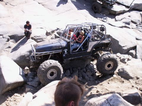 1989 Ford Bronco - This heavily modified Jeep navigates a challenging rocky obstacle course with multiple vehicles present.