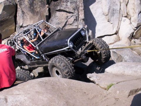 1989 Ford Bronco - Modified Jeep navigating difficult rocky terrain with assistance from a tow strap.