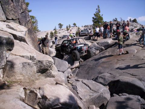 1989 Ford Bronco - Off-road vehicle navigating a challenging rocky trail with onlookers present.