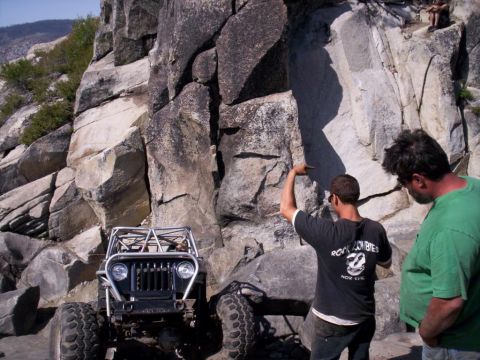 1989 Ford Bronco - Two men observe a modified off-road vehicle positioned on a rocky incline.