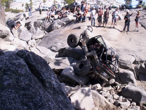1989 Ford Bronco - A group of spectators watches as an off-road vehicle gets stuck on a rocky incline.