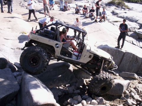 1989 Ford Bronco - Custom off-road vehicle tackles a challenging rock crawling course with spectators observing.